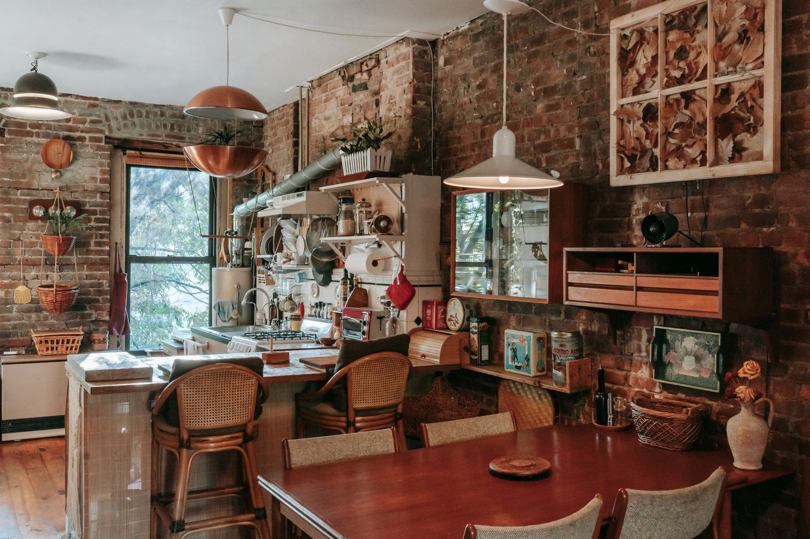 Cucina e sala da pranzo di un'abitazione d'epoca con muri in mattoni, tavolo in legno e sgabelli