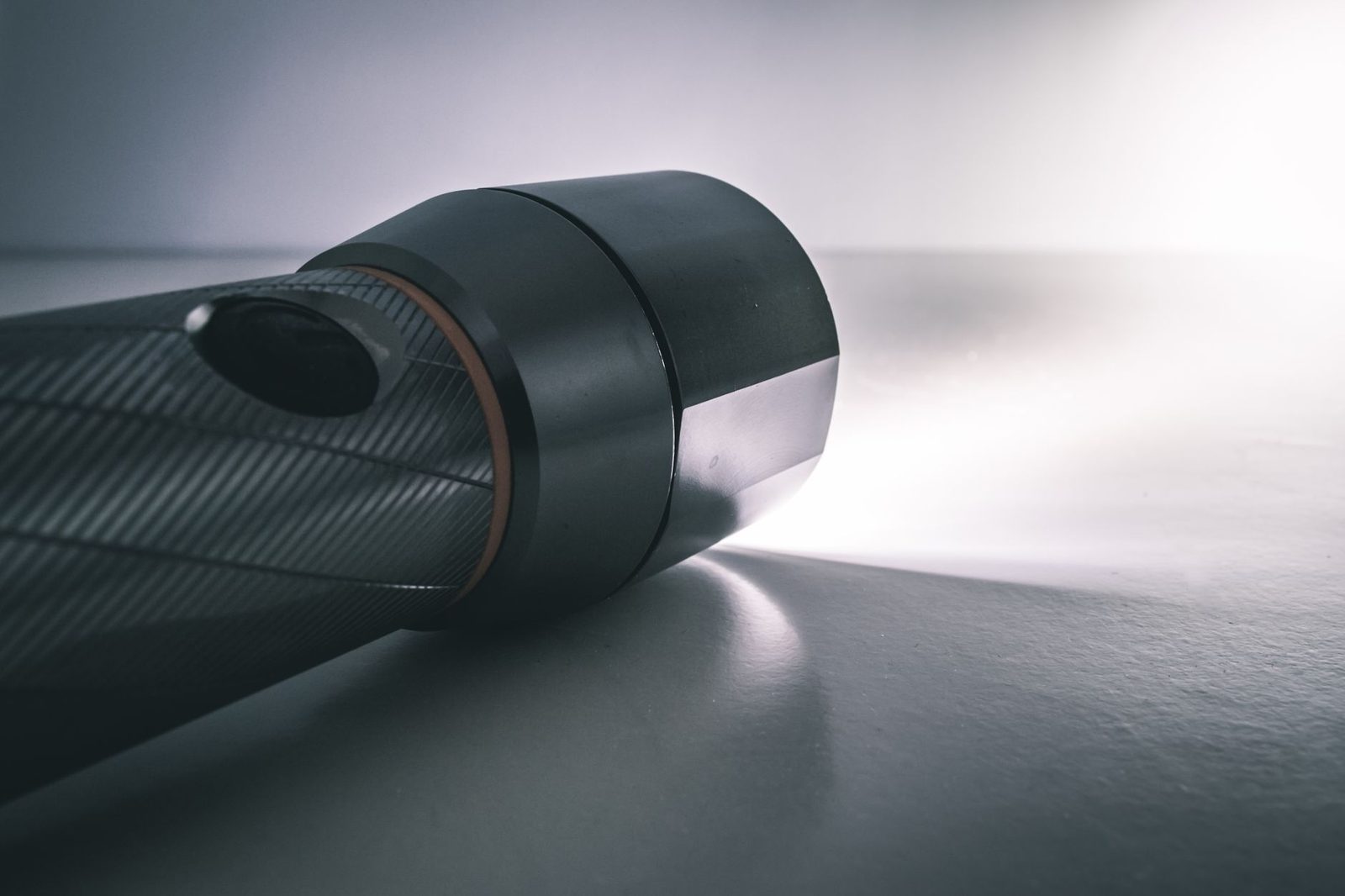 Lampe de poche allumée posée sur une surface claire, faisceau lumineux éclairant le sol