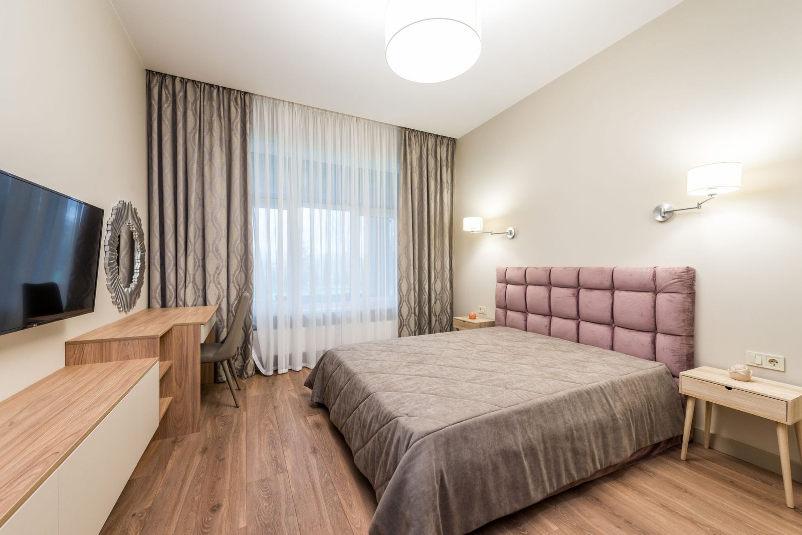 Modernes Schlafzimmer mit Doppelbett, rosafarbenem Kopfteil, Parkettboden und hellen Vorhängen